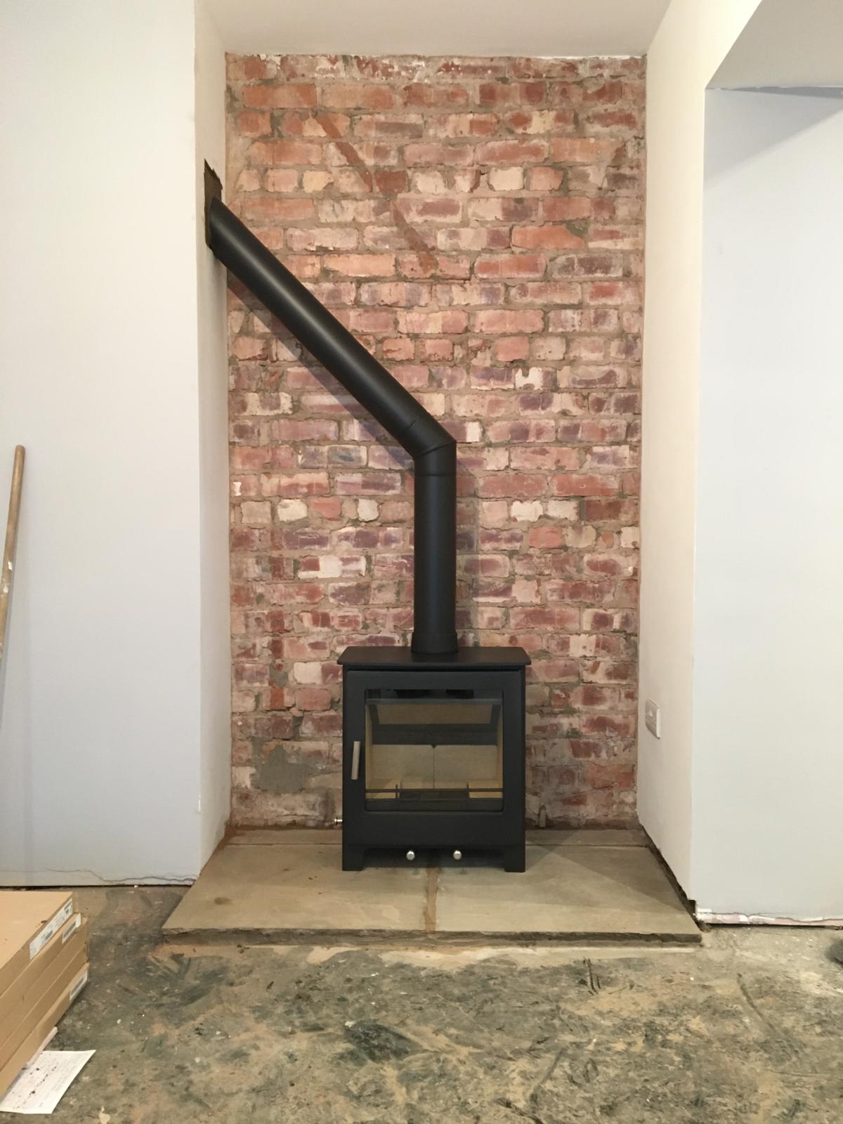 Stove with exposed brick and angled flue pipe